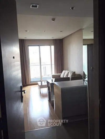 Modern living room with balcony and natural light, featuring sleek furniture and open layout.