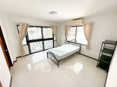 Spacious bedroom with large windows and natural light in modern apartment.