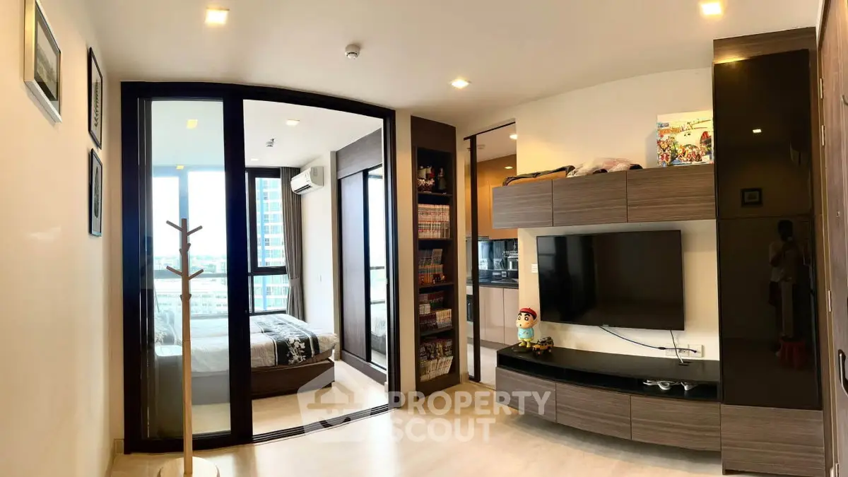 Modern living room with sleek entertainment center and view into cozy bedroom