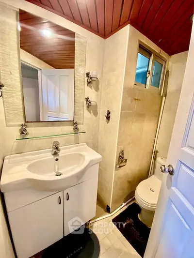 Compact bathroom with modern fixtures and wooden ceiling accents