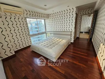 Spacious bedroom with modern design and large windows offering city views.