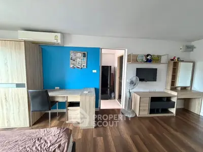 Modern furnished bedroom with wooden flooring and blue accent wall