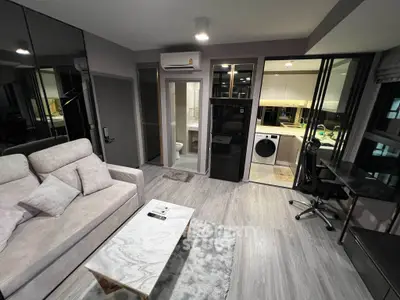 Modern living room with sleek design, featuring a cozy sofa, marble coffee table, and open kitchen with appliances.