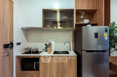 Modern kitchen with sleek appliances and wooden cabinetry, featuring a stainless steel fridge and built-in microwave.