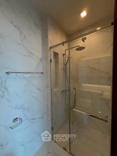 Luxurious bathroom with elegant marble tiles and modern glass shower enclosure.