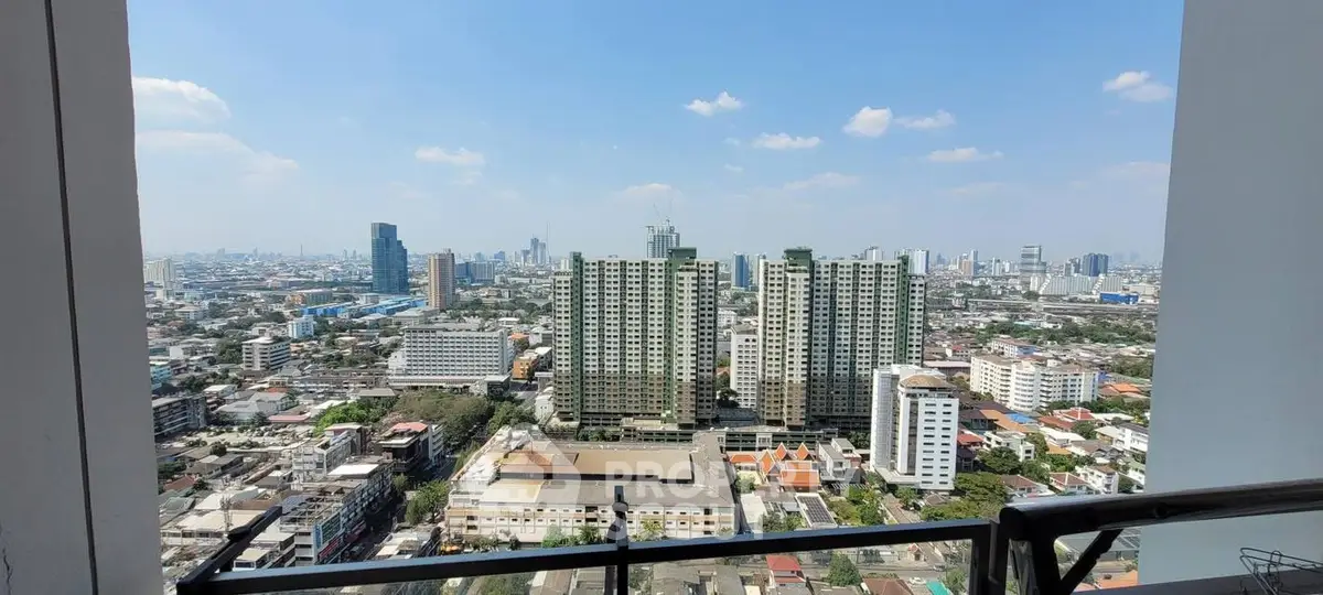 Stunning cityscape view from high-rise balcony showcasing urban skyline and clear blue sky.