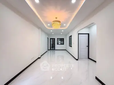 Spacious modern living room with elegant chandelier and glossy white flooring