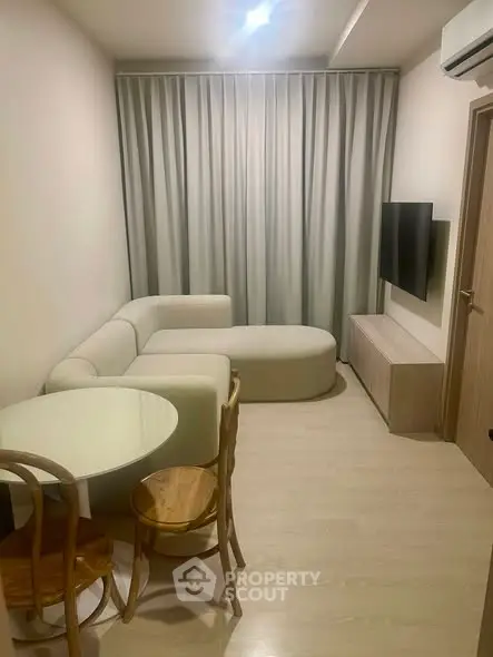 Modern living room with cozy sofa, round table, and wall-mounted TV in a stylish apartment.
