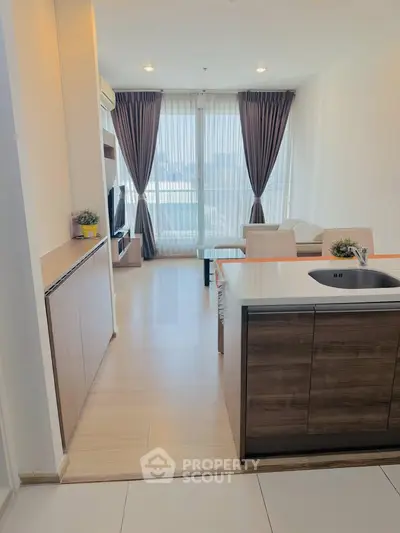 Modern open-layout living room with kitchen island and large windows in a stylish apartment.