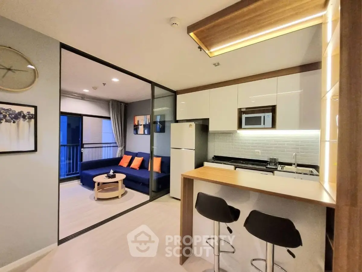 Modern open-layout kitchen and living room with stylish decor and balcony view.