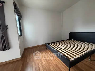 Spacious bedroom with wooden flooring and modern bed frame, perfect for customization.
