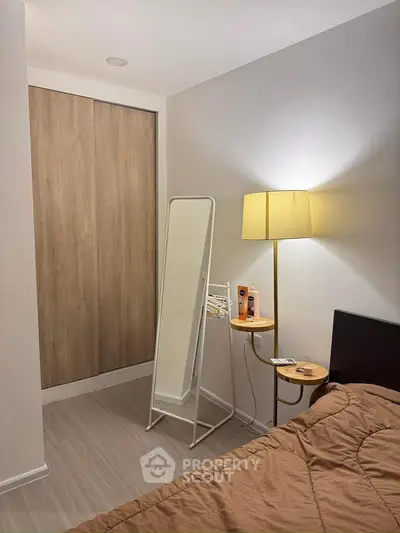 Cozy bedroom with modern decor, featuring a standing mirror and warm lighting.