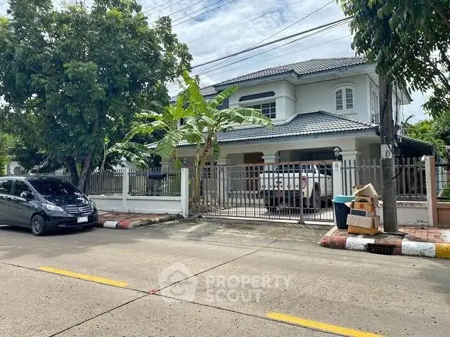 Charming suburban house with lush greenery and secure gated entrance, perfect for family living.