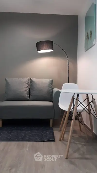Modern living room with stylish gray sofa, sleek floor lamp, and minimalist white table for contemporary living.