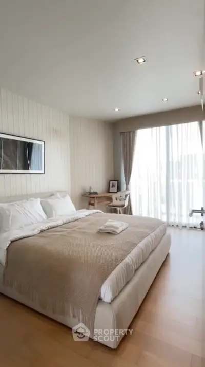 Spacious bedroom with modern decor and large window offering natural light.