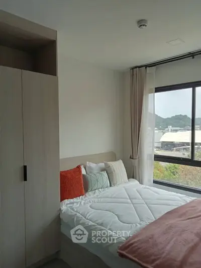 Cozy bedroom with large window offering scenic views and modern furnishings.