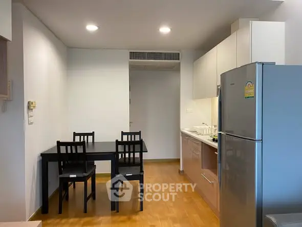 Modern kitchen with dining area, featuring sleek appliances and wooden flooring.