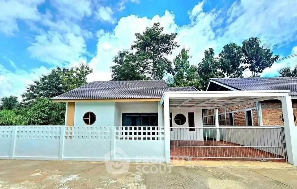 Charming single-story home with modern design and spacious carport, surrounded by lush greenery.