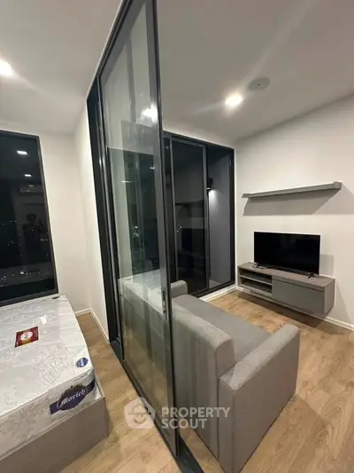 Modern studio apartment with sliding glass divider, cozy living area, and sleek TV setup.