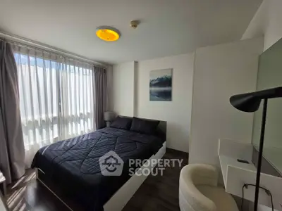 Cozy bedroom with modern decor and ample natural light from large window.