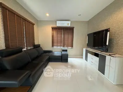 Modern living room with sleek black leather sofa and large flat-screen TV, featuring elegant wooden blinds and glossy tile flooring.