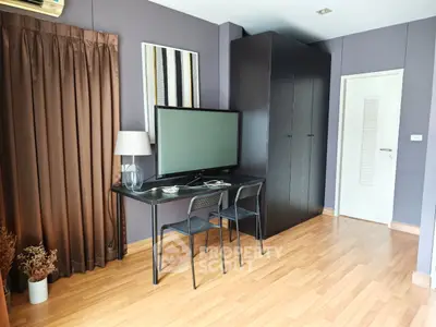 Modern living room with sleek furniture and large TV, featuring elegant wooden flooring and stylish decor.