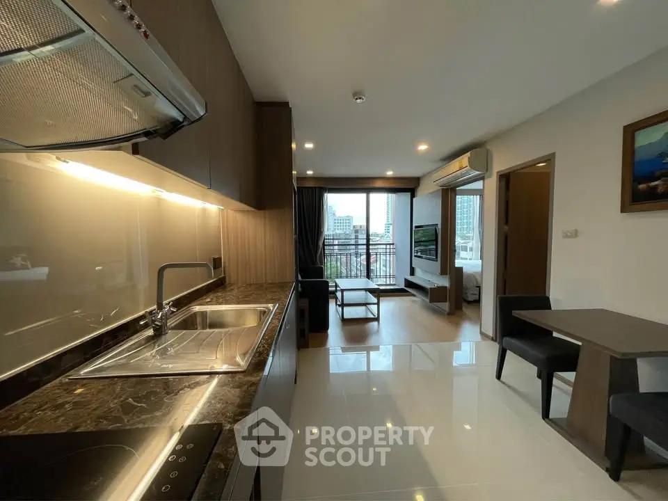 Modern open-layout kitchen and living room with city view balcony in luxury apartment.