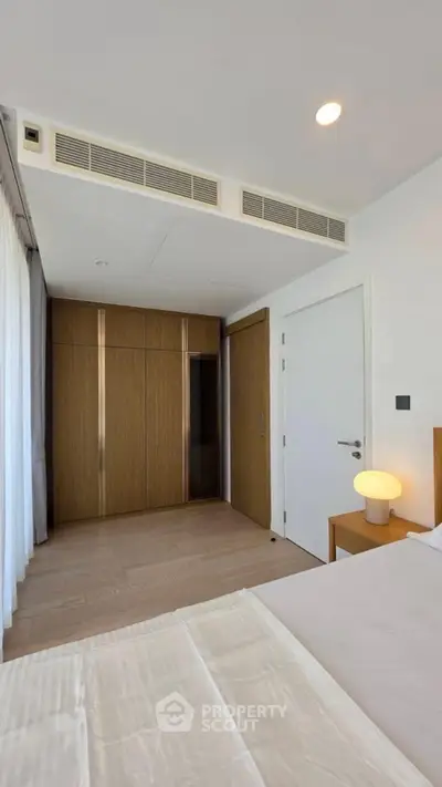 Modern bedroom with wooden wardrobe and sleek design in a contemporary apartment.