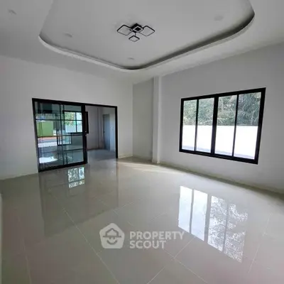 Spacious modern living room with large windows and elegant ceiling design.
