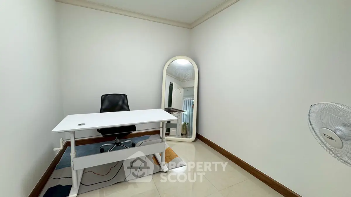 Modern minimalist study room with sleek desk and chair, featuring a large mirror and stylish decor.