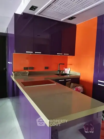 Modern kitchen with vibrant purple and orange cabinets and sleek countertops