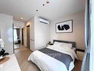 Modern bedroom with stylish decor and ample natural light, featuring a cozy bed and mirrored wardrobe.