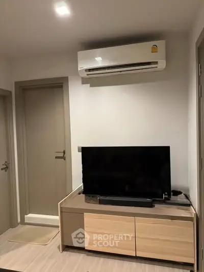 Modern living room with sleek TV setup and air conditioning unit.