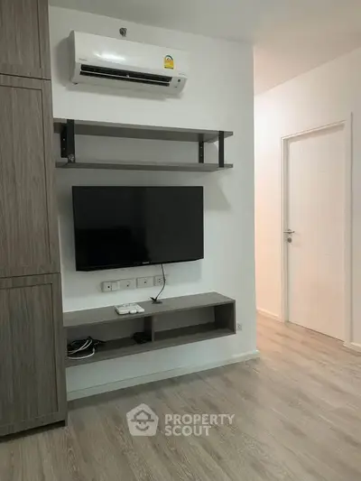 Modern living room with wall-mounted TV and air conditioning in a stylish apartment.