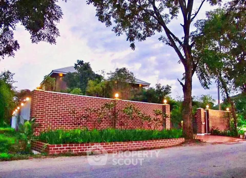 Charming brick-walled property with lush greenery and ambient lighting, offering serene and private living.