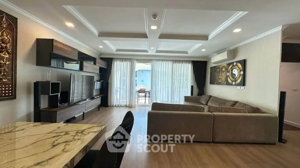 Spacious modern living room with elegant decor and large windows leading to a balcony.