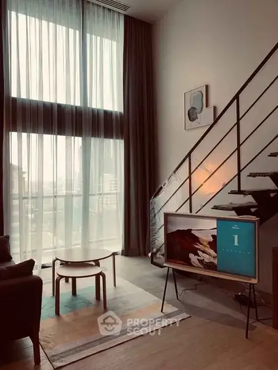 Modern living room with high ceilings, large windows, and stylish staircase in urban apartment.