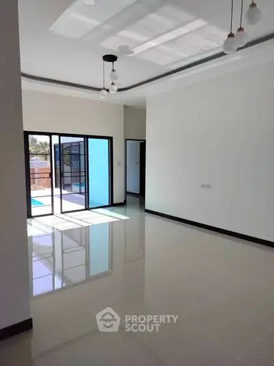 Spacious modern living room with large windows and glossy tiled floors, offering a bright and airy ambiance.