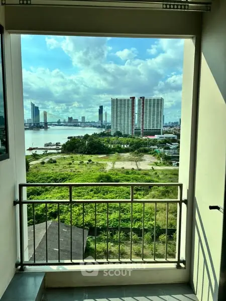 Stunning cityscape view from a high-rise balcony overlooking lush greenery and river.