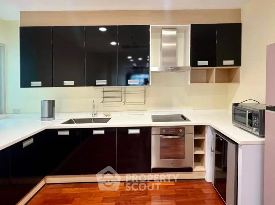 Modern kitchen with sleek black cabinets, built-in oven, and stylish open layout.