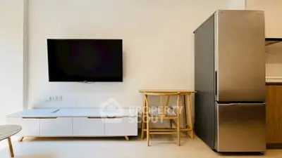 Modern living room with sleek TV, stylish furniture, and stainless steel fridge for contemporary living.