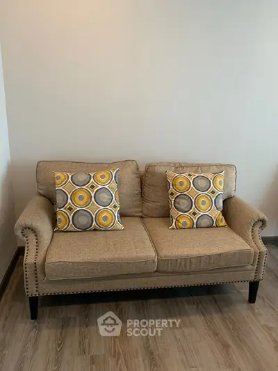 Cozy living room with stylish beige sofa and decorative pillows on wooden flooring.