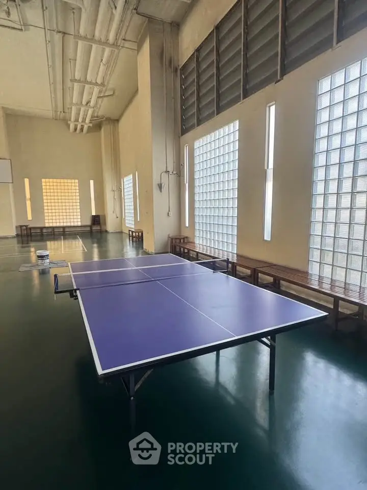 Spacious indoor recreational area with table tennis setup and ample seating, perfect for leisure activities.