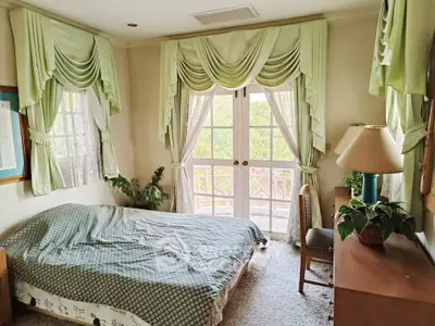 Charming bedroom with elegant drapes and garden view, perfect for serene living.