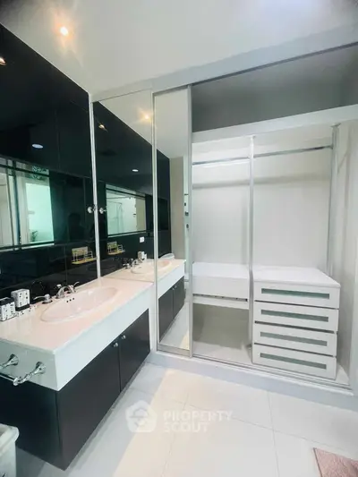 Modern bathroom with sleek black and white design, featuring dual sinks and spacious storage.