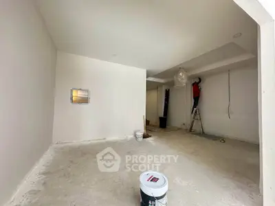 Spacious interior under renovation with fresh white walls and ceiling lights being installed.