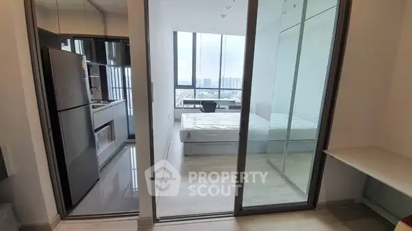 Modern apartment with sleek kitchen and bright bedroom featuring floor-to-ceiling windows and city view.