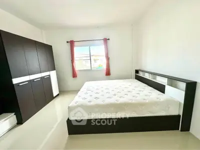 Spacious bedroom with modern furnishings and large window for natural light.
