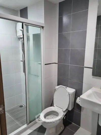 Modern bathroom with sleek gray tiles and glass shower enclosure
