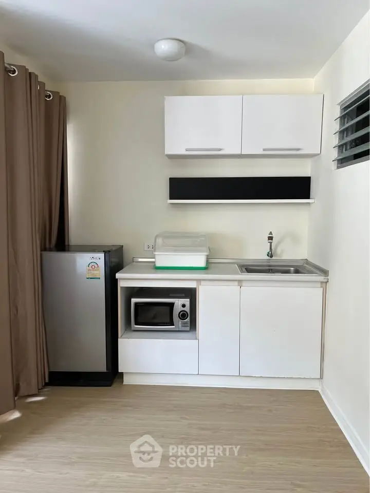 Compact kitchen with modern appliances and sleek cabinetry in cozy apartment.